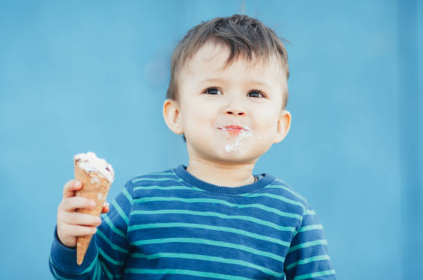 istock child outdoors, on a blue background eating ice cream 1134920714