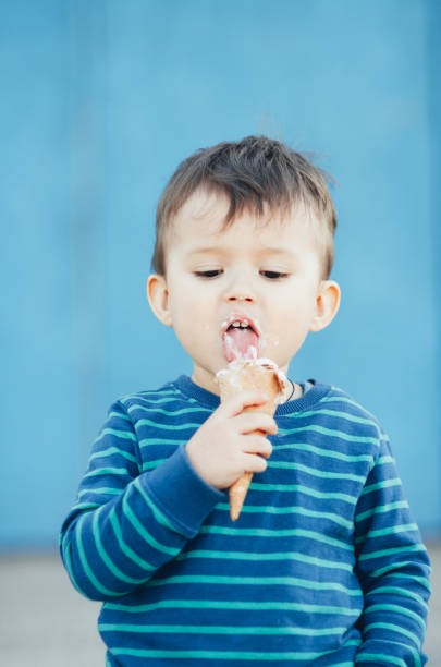 istock child outdoors, on a blue background eating ice cream 1134920883