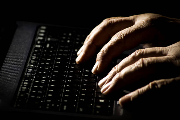 conceito do perigo no internet, as mãos de um homem idoso em um teclado do portátil - idoso na internet - fotografias e filmes do acervo