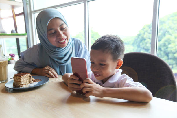 istock A Muslim Mother With Her Son Looking Smart Phone 1134925892
