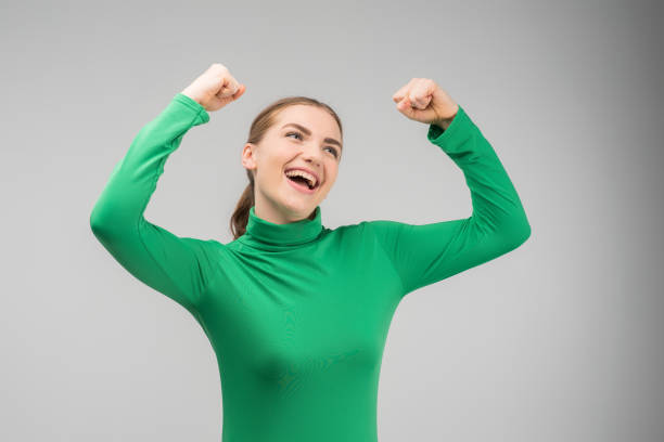 Happy cheerful young woman looking up with hands up and smiling with opened mouth .- Image