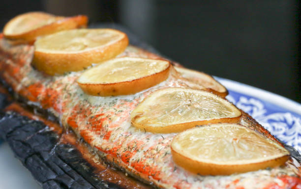 salmone alla griglia con limone e aneto cotti su una tavola di cedro - lemon fruit portion citrus fruit foto e immagini stock