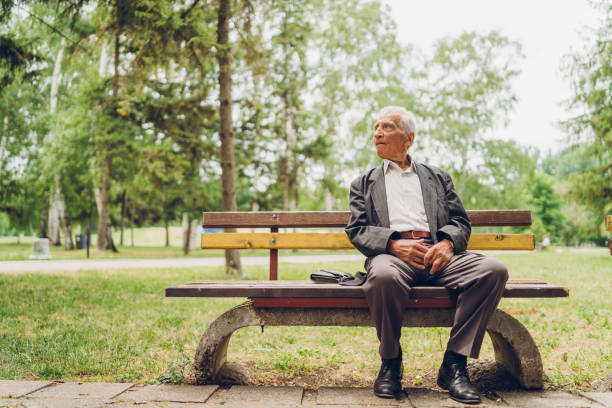 homme aîné s'asseyant sur un banc de parc - park bench photos et images de collection