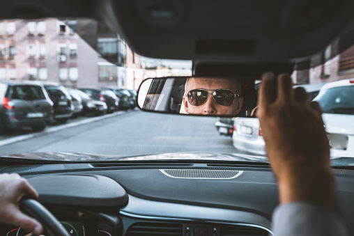 road trip, transport and people concept - man driving car adjusting rearview mirror.Man sitting in a car and adjusting rearview mirror, car interior .