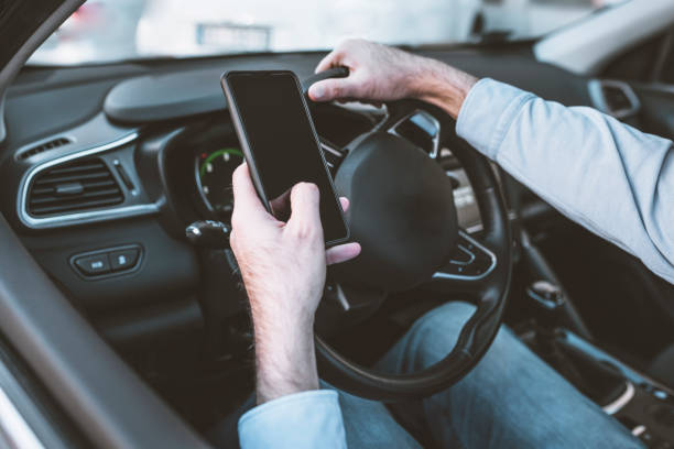 guida pericolosa durante la scrittura di sms. uomo con cellulare in mano e giovane donna a guida in auto in autostrada. - driving women rear view sitting foto e immagini stock