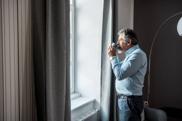 istock Senior man drinking coffee and looking outside the window 1134933796