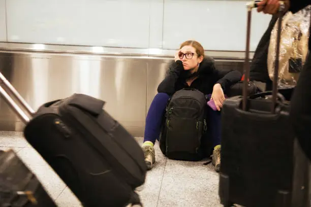 Photo of Distraught woman sits in airport while travelers pass her