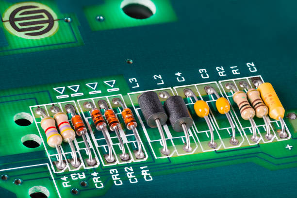 Inductors, capacitors, resistors and diodes on green PCB. Black coils.
