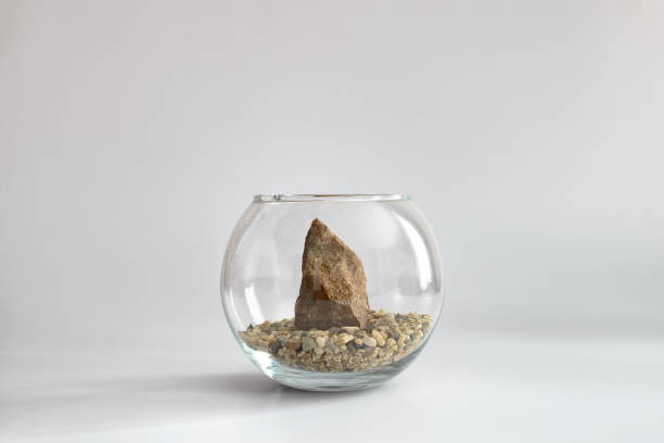 Granite stone on sand in glass aquarium on white background. Minimal concept.