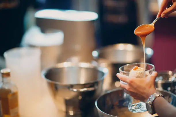 Woman pouring caramel syrup over  ice cream.
