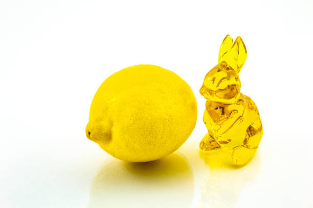 Yellow glass Easter bunny with a lemon on a white background.