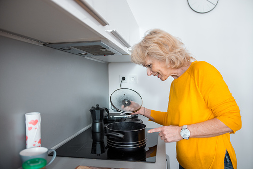 Senior woman checking to see if the spaghetti are cooked yet