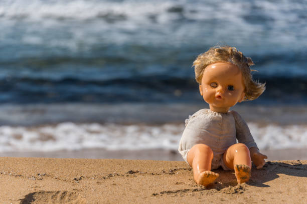 istock Old Broken Toy Doll Sitting on a Beach in Italy 1134952461