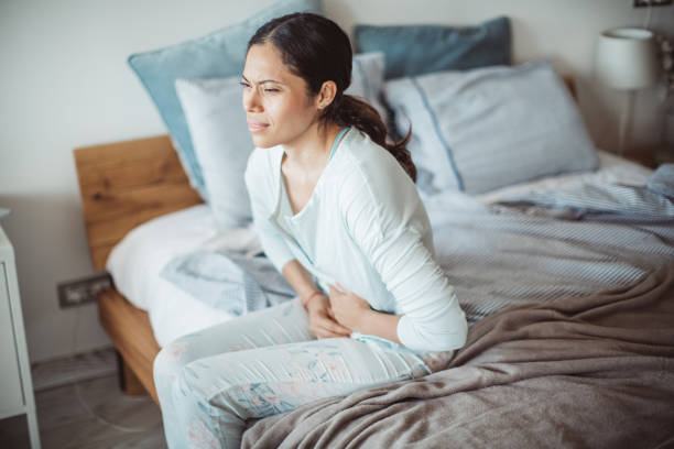 Stomach pain attack Woman with abdomen problems in bed, she use hands to massage painful place stomachache stock pictures, royalty-free photos & images