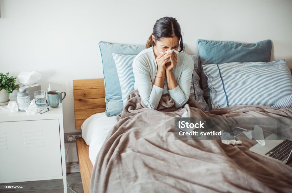 Flu attack Woman with flu in bed, she use home medicine to handle sickness Cold And Flu Stock Photo