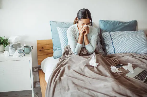 Woman with flu in bed, she use home medicine to handle sickness