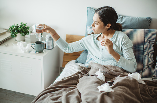 Woman with flu in bed, she use home medicine to handle sickness