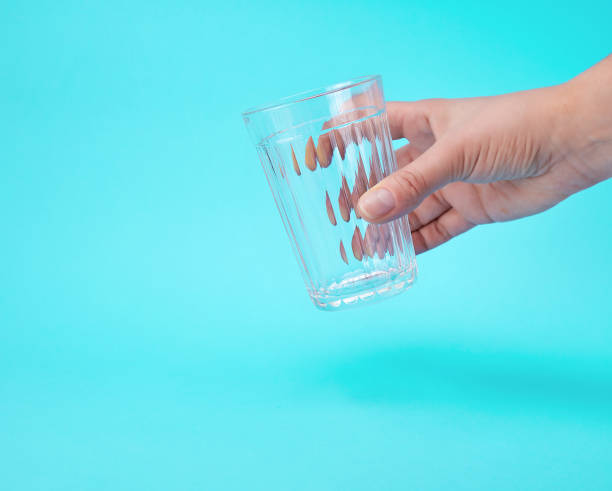 istock woman's hand holding an empty transparent glass 1134955511