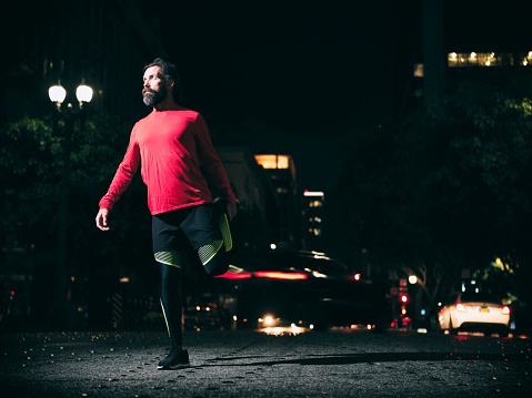 A man running in the downtown area of Los Angeles at night.