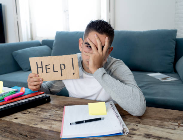 istock Young tired and stressed student working on his homework, masters feeling desperate and frustrated asking for help. In over Education, learning difficulties, finals exams and emotional stress concept. 1134957125