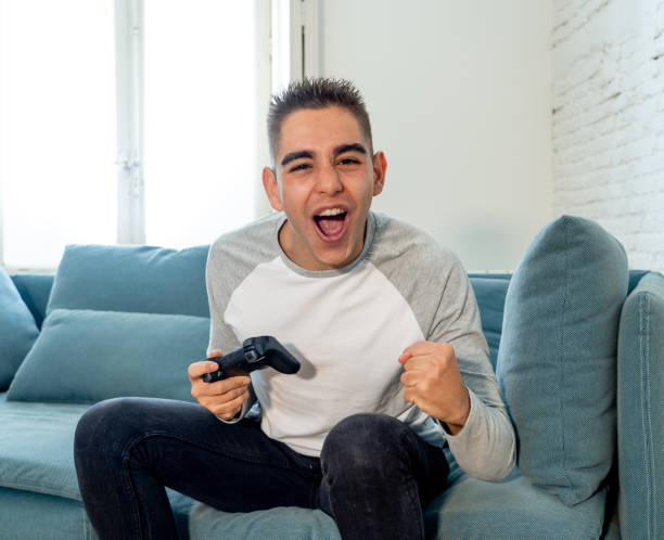 istock Portrait of young student man playing video games having fun winning the game using wireless remote joystick with freak intense happy face in Male game addiction to console play station and video. 1134957135