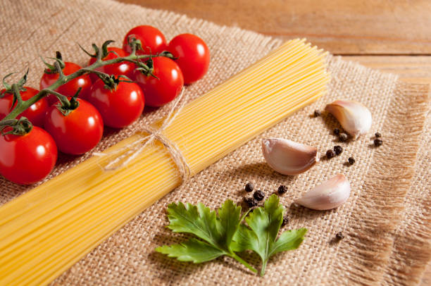 istock Spaghetti, tomatoes cherry, pepper, garlic and  parsley on burlap. 1134958141