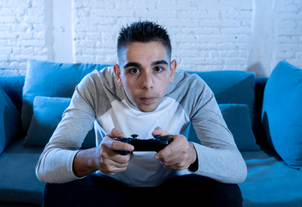 istock Portrait of young student man playing video games at night using wireless remote joystick with freak intense addicted face having fun in Male game addiction to console play station and video. 1134960068