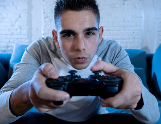 istock Portrait of young student man playing video games at night using wireless remote joystick with freak intense addicted face having fun in Male game addiction to console play station and video. 1134960074