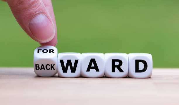 Hand turns a dice and changes the word "BACKWARD" to "FORWARD". stock photo