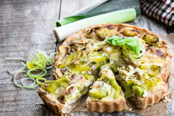 Leek  tart with bacon and cheese on wooden table