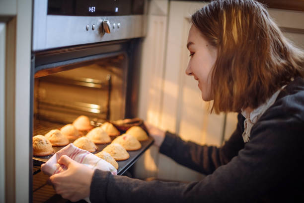 istock Happy girl getting cakes from oven at the kitchen 1134961433