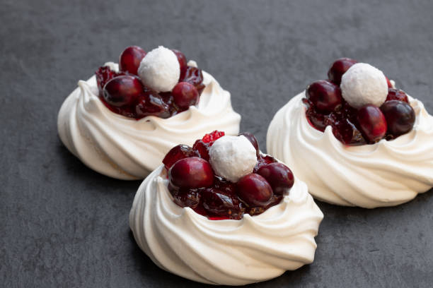 istock Mini Pavlova meringue nests with fresh and sugared cranberry on black stone background 1134961477