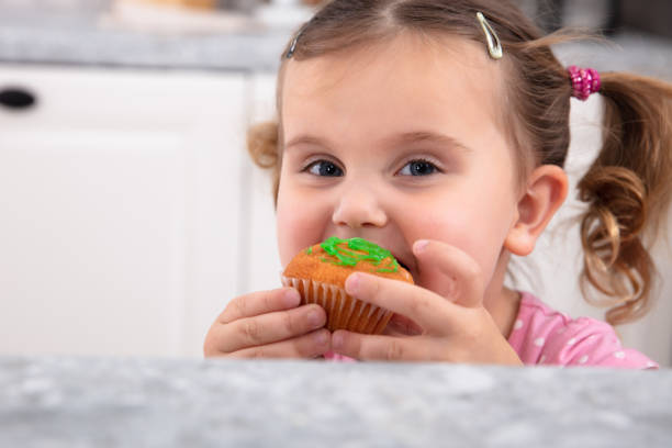 istock Small Girl Eating A Cupcake In The Kitchen 1134962150