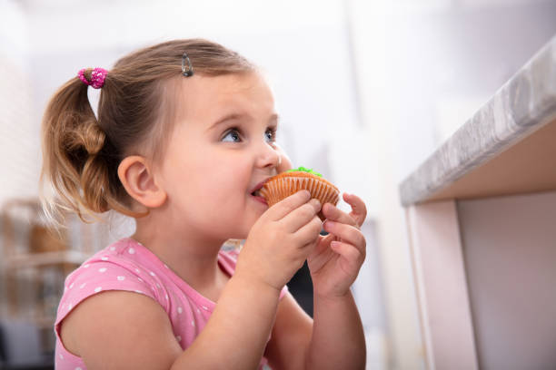 istock Girl Taking A Bite Of Cupcake In The Kitchen 1134962156