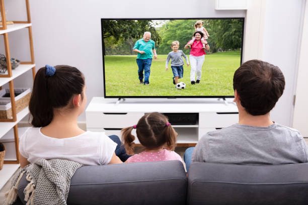 istock Family Sitting On Couch Watching Television 1134962176