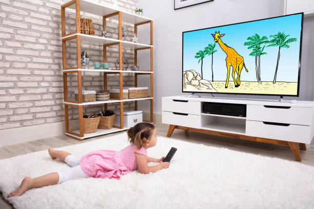 istock Little Girl Lying On Carpet Watching Cartoon 1134962177