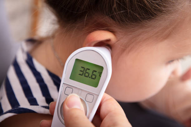 デジタル体温計と女の子の耳を手でチェック - thermometer ストックフォトと画像
