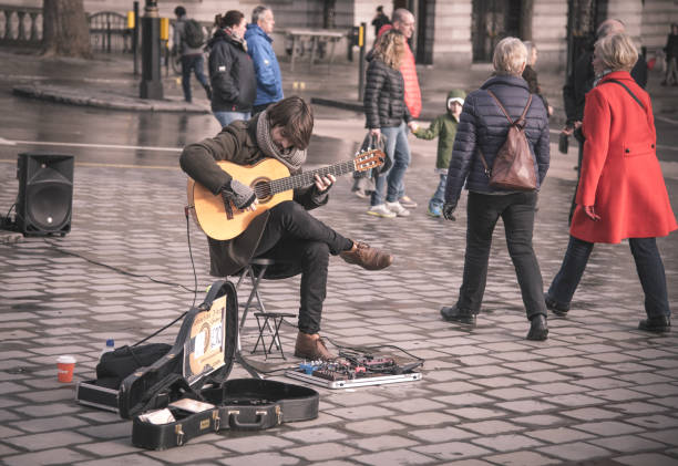 London, England - March 6 2018: Young guitarist street musician performing on the streets of London to entertain the people walking around