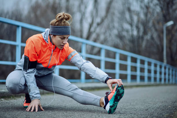 istock Female athlete stretching her leg and warming up on the road. 1134967577