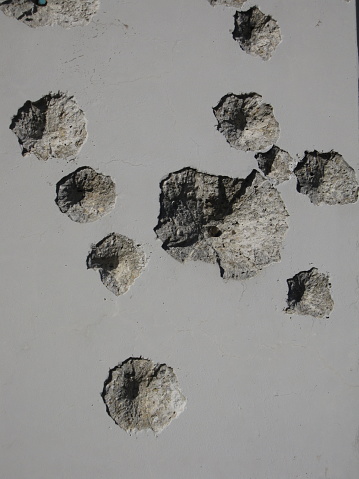 A number of bullet holes ridden a concrete wall. Photograph taken in Slovakia.