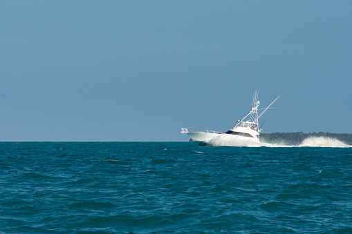 White luxury yacht sport fisher with breaking bow wave.