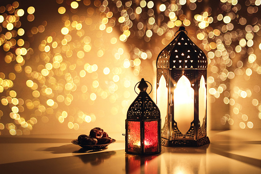 Linternas árabes ornamentales con velas ardientes. Brillantes luces bokeh doradas. Plato con fecha fruta sobre la mesa. Tarjeta de felicitación para las vacaciones musulmanas Ramadán Kareem. El fondo de la cena de Iftar. photo