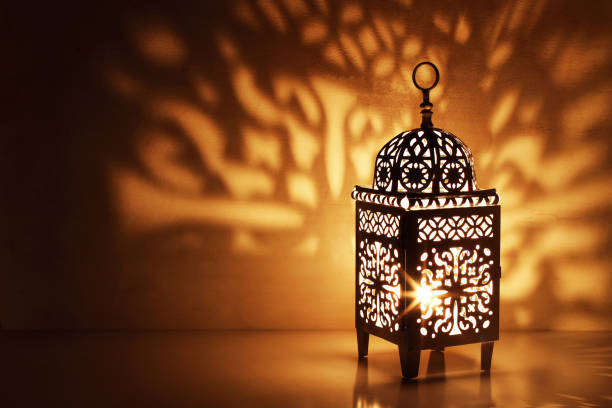 istock Silhouette of Moroccan ornamental lantern with burning glowing candle. Decorative shadows. Festive greeting card, invitation for Muslim holy month Ramadan Kareem. Festive night background. 1134972518