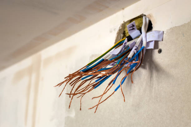 istock Electrical exposed connected wires protruding from socket on white wall. Electrical wiring installation. Finishing works in renovated apartment. 1134973712