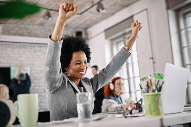 Cheerful African American businesswoman celebrating success while using computer in the office.