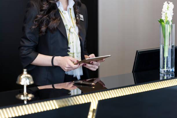 hotel receptionist checking up room status on digital tablet - hotel desk reception imagens e fotografias de stock