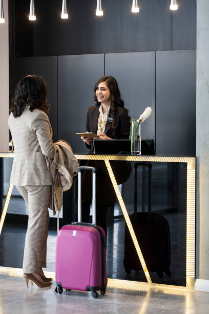 Businesswoman Checking In At Hotel Reception Businesswoman Checking In At Hotel Reception hotel reception hotel service technology stock pictures, royalty-free photos & images