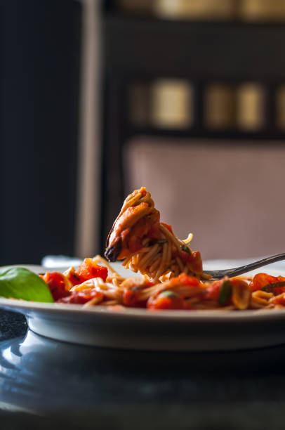 Marinara with mussels Whole wheat spaghetti with Mussels in marinara sauce on a table setting cooked selective focus vertical pasta stock pictures, royalty-free photos & images