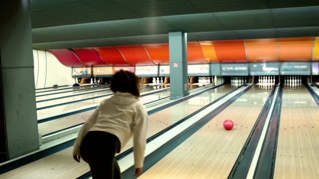Young Woman in club for bowling is throwing ball.