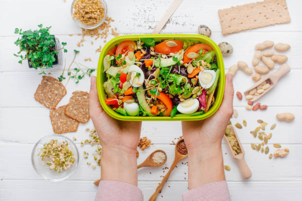 istock Female hands holding open lunch box with vegetable salad 1134983025